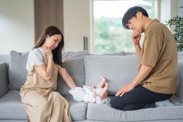 赤ちゃんを前に首をかしげる夫婦